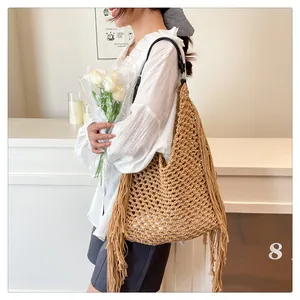 Detail of bohemian hollow hand-woven tote bag with long tassels and black shoulder strap