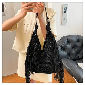 Close-up of black bohemian hollow woven tote bag with long fringe and leather strap