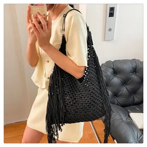 Close-up of black mesh crochet tote bag featuring long decorative fringe and leather strap
