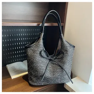 Κοντινό πλάνο σε τσάντα tweed με δερμάτινες λαβές και κομψή λεπτομέρεια με φιόγκο