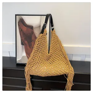 Detail of yellow hollow hand-woven tote bag with long fringe and black leather strap