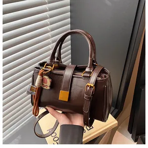 Detail of dark brown leather handbag with golden buckle and cute hippo charm