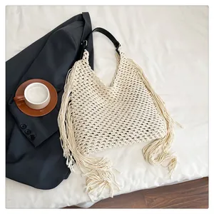 Detail of bohemian hollow knit bag featuring long tassels and black leather strap
