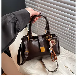 Detail of vintage brown leather handbag with gold buckle and cute bear pendant charm