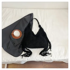 Detail of black woven tassel bag with mesh crochet pattern and leather strap