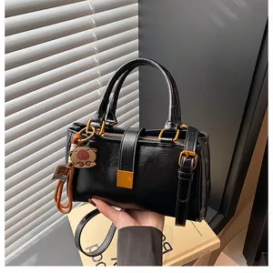Close-up of black glossy leather handbag featuring gold hardware and animal charm