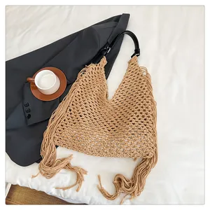 Detail of khaki crochet woven beach tote bag with long tassels and black leather strap