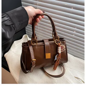 Close-up of brown crossbody bag featuring a gold square buckle and cat tassel charm