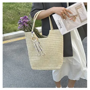 Detail of woven straw tote bag featuring blue evil eye tassel and decorative flowers