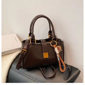 Detail of a dark brown crossbody bag with gold hardware and a cute bear charm pendant