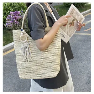 Detail of woven beach tote bag featuring evil eye charm and white tassel ornament