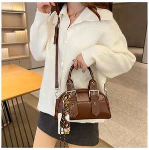 Gros plan du sac Boston marron rétro avec doubles poignées et texture en cuir poli