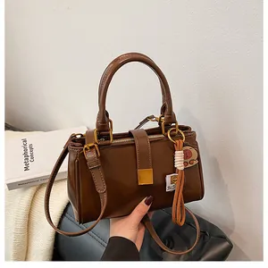 Close-up of vintage brown leather handbag with gold metal clasp and tassel charm detail