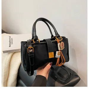 Detail of a black glossy PU leather handbag with gold buckle and adjustable strap