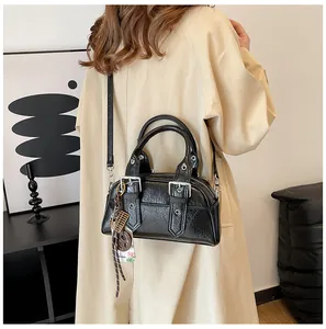 Détail du sac à main en cuir texturé noir avec boucles argentées et pendentif à franges