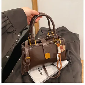 Detail of dark brown polished handbag featuring gold hardware and a cute bear charm