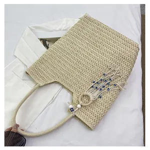Detail of beige straw woven tote with blue evil eye bead charms and wood ring detail