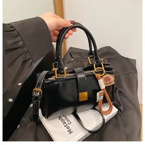 Detail of black PU leather handbag with gold hardware and a cute character bag charm