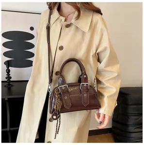 Détail d'un sac porté épaule en similicuir marron foncé avec texture brillante et boucle