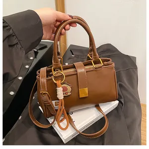 Detail of vintage brown PU leather handbag with gold buckle and cute charm accessory