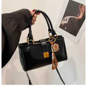 Close-up of black leather handbag with gold hardware and cartoon bear charm