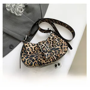 Detailed view of leopard print hobo bag with metal buckle next to a smartphone for scale