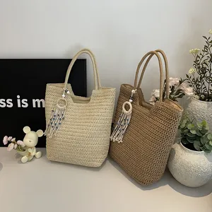 Minimalist woven straw beach tote bag in beige and brown with tassel charms