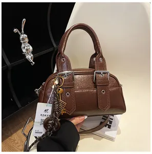 Gros plan d'un sac à main vintage en cuir marron avec boucles argentées et pendentif chic