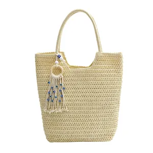 Large beige straw tote bag with evil eye tassel charm and wooden ring details