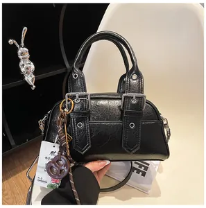 Gros plan détaillé d'un sac à main noir brillant plissé avec boucles argentées et breloques