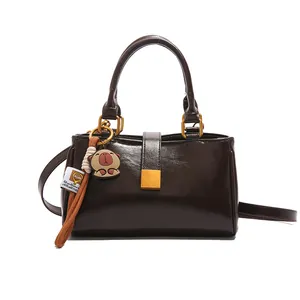 Minimalist dark brown leather handbag with golden buckle and cute capybara pendant charm