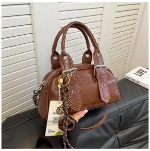 Détail du sac à bandoulière marron vintage avec boucles décoratives et œillets