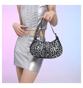 Detail of leopard print shoulder bag with silver buckle held by model in silver outfit