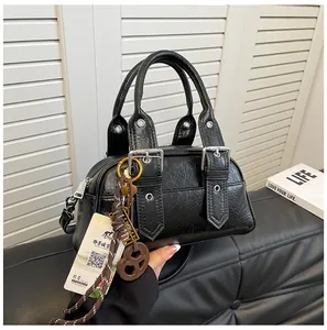 Détail d'un sac à main noir en cuir grainé avec boucles argentées et breloque