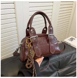 Détail du sac Boston en cuir verni marron foncé avec ferrures argentées et charms