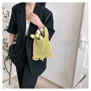 Detail of yellow handmade woven tote bag featuring decorative tassels and cotton knit texture