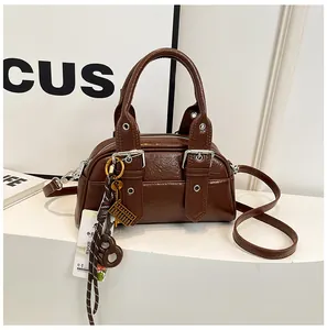 Détail du sac à main en cuir marron foncé avec boucles argentées et pendentif tressé