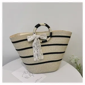 Détail d'un sac cabas en paille à rayures noires avec un nœud en dentelle élégant