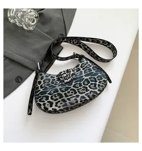 Close-up of leopard print hobo bag with adjustable strap on a textured surface
