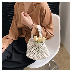 Detail of white handmade crochet bucket bag with hollow mesh pattern and top handle