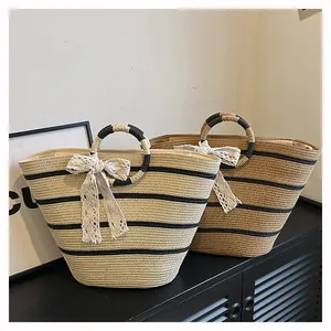 Détail de sacs cabas en paille avec poignées rondes et nœuds en dentelle pour plage
