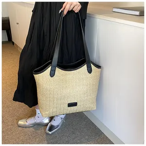 Sac fourre-tout en paille à lanières noires porté par un mannequin en robe noire