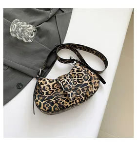 Detailed view of leopard print crossbody bag with silver buckle on a minimalist background