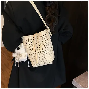 Detail der cremefarbenen Laser-Cut-Eimertasche mit weichem Plüsch-Hundeanhänger