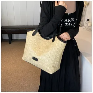 Détail du sac cabas beige en paille tressée avec anses et bordures en cuir noir