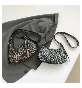 Detail of crescent leopard print shoulder bags in brown and grey over a grey blazer