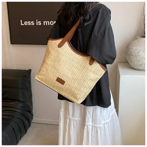 Détail d'un grand sac cabas en paille avec bandoulières en cuir sur un mannequin