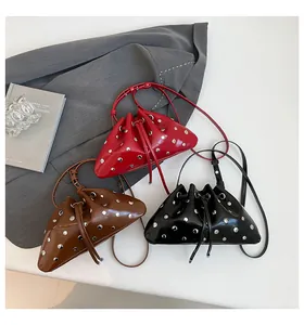 Detail of trendy bucket bags with metal eyelets and drawstring in red, brown, and black