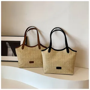 Détail de sacs cabas en paille tressée avec anses en cuir et texture verticale