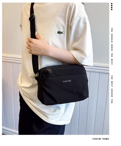 Detail of adjustable strap and white logo on black waterproof nylon crossbody bag